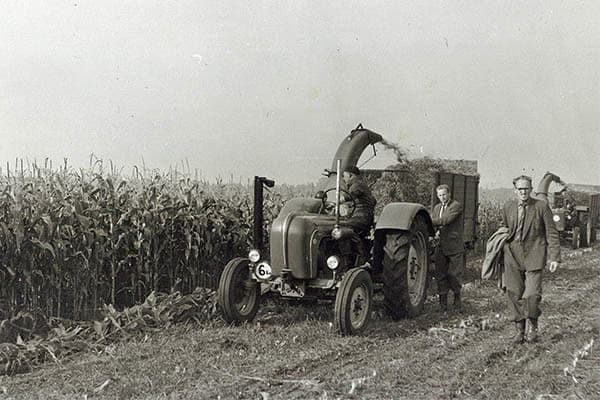 De wagens waar de mais in werd geblazen, waren zelflossend. Met een ketting draaide de boel er vanzelf uit. In de praktijk viel dat een beetje tegen, de boel liep regelmatig vast waardoor alsnog de schep en opgestroopte mouwen eraan te pas moesten komen. - Foto: Misset