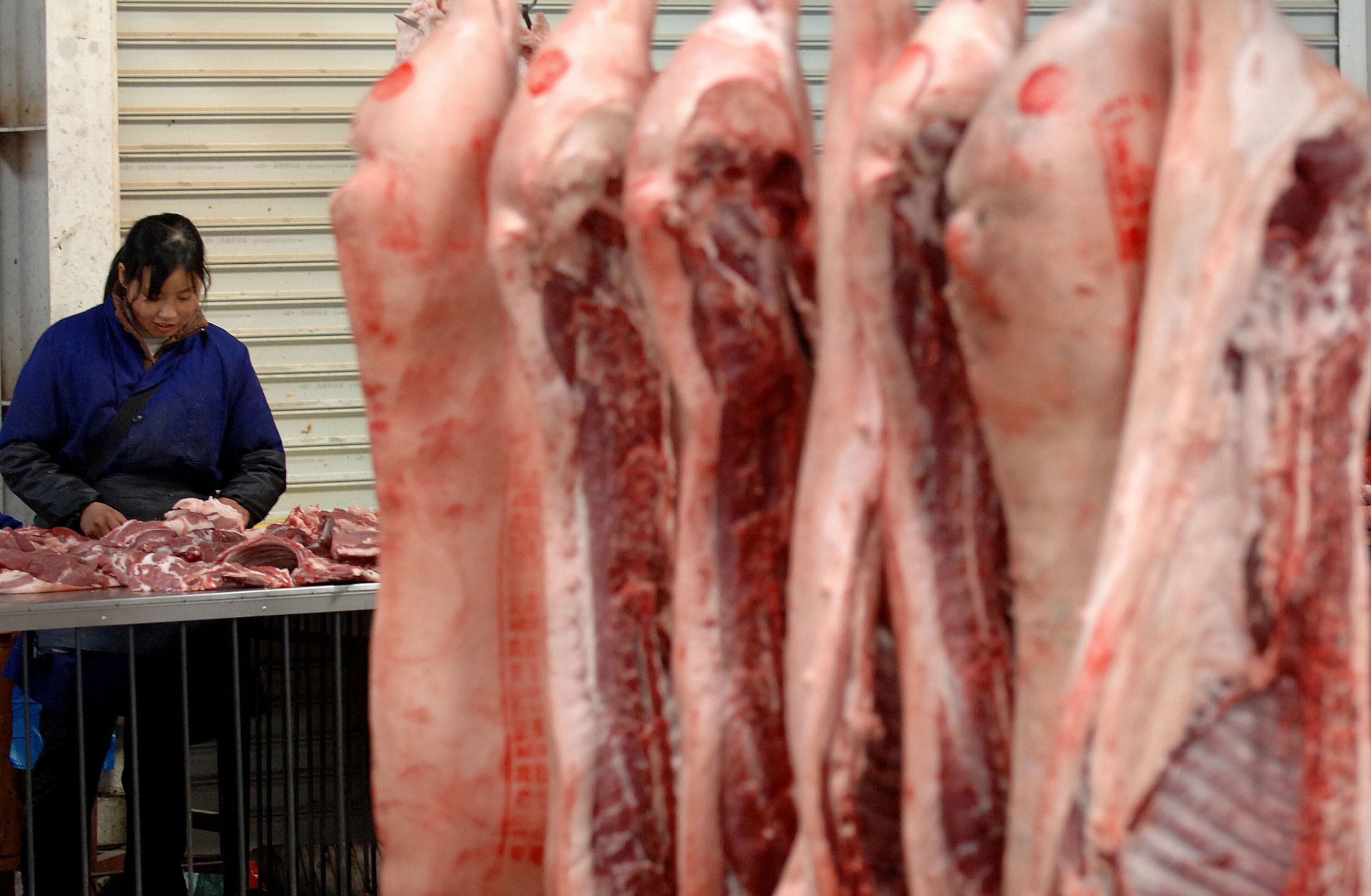 2006-12-04 12:47:00 A vendor works beside her display of fresh pork for sale at wholesale market in Hefei, 04 December 2006, in eastern China's Anhui province. China's entry into the WTO on December 11, 2001 was welcomed by its trading partners as finally bringing one of the world's fastest-growing economies into the bosom of the trading system but as the five-year WTO honeymoon draws to a close, the United States and Europe are intensifying pressure for the emerging giant to play fair by the rules of global trade. With another winter season underway in China, consumers are facing a rise in prices for basic commodities such as grain, cooking oil, eggs and pork. AFP PHOTO / (CHINA OUT GETTY OUT)