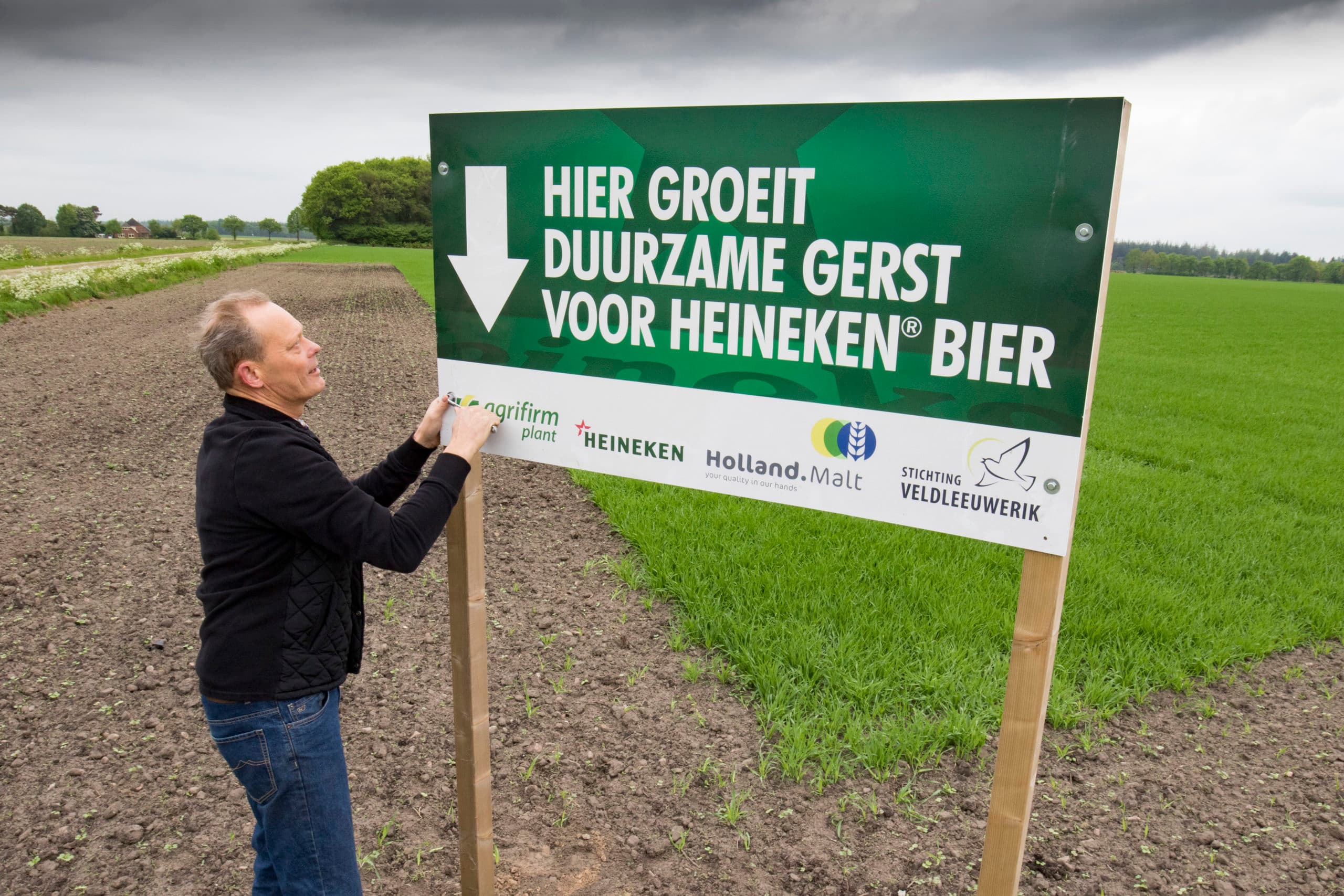 Erik Huizing plaatst het bord in zijn gerst.  Zo laat ik burgers zien dat een boerenbedrijf niet alleen draait om economie, maar ook om duurzaamheid, natuur en milieu.  - Foto: Jan Willem van Vliet