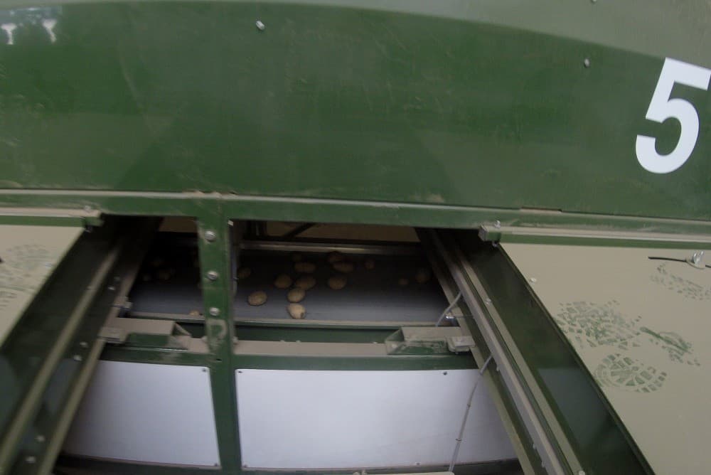 Alle banden gaan langs de openingen voor de verschillende maten. Het aantal banden bepaalt de capaciteit van de machine. Deze met acht banden heeft een capaciteit van 8 tot 12 ton per uur.