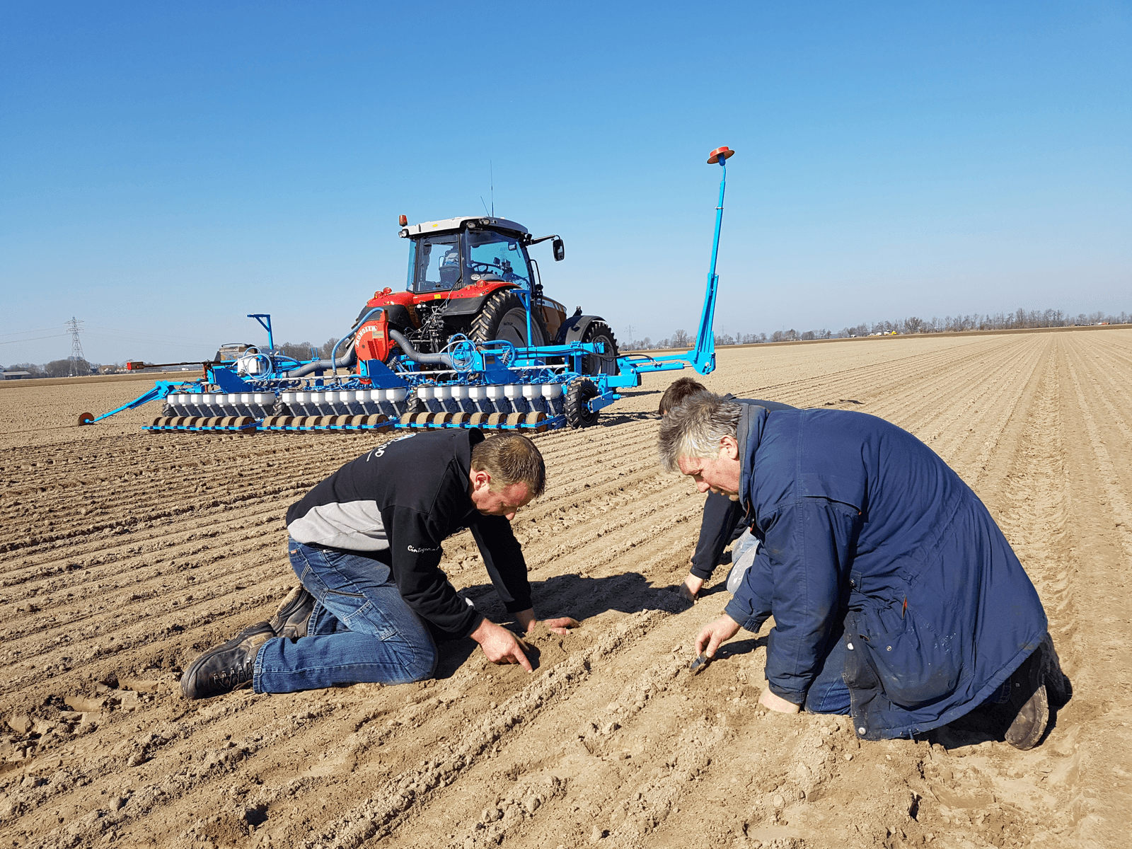Jan de Gorter, medewerker van loonbedrijf Cintégro (links), bekijkt het uien zaaien in Marknesse met uienteler Hendrik Nijdam en diens zoon Henyo (achter Hendrik).<br /><em>Foto: Sytze Bakker</em>