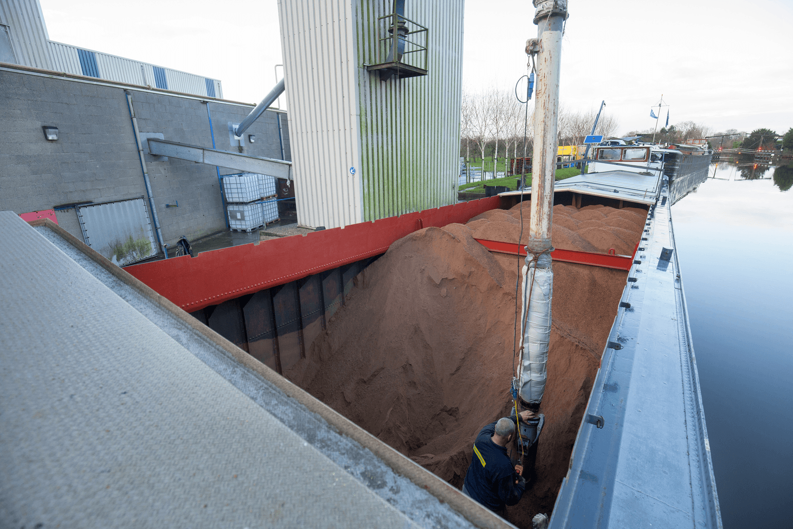 Een schip met voergrondstof wordt gelost bij de fabriek van De Samenwerking in Haastrecht. Het bedrijf viert zijn honderdjarig bestaan.