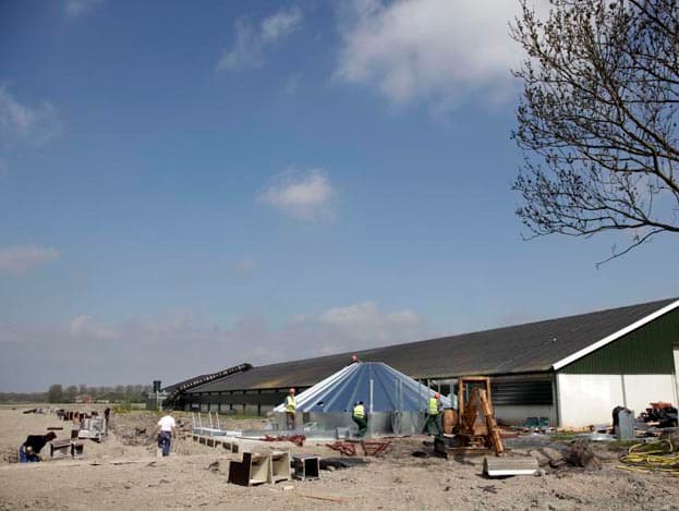 Langs de dakrand wordt een bordes bevestigd. De bouwlieden tillen het bordes naar de juiste plek.