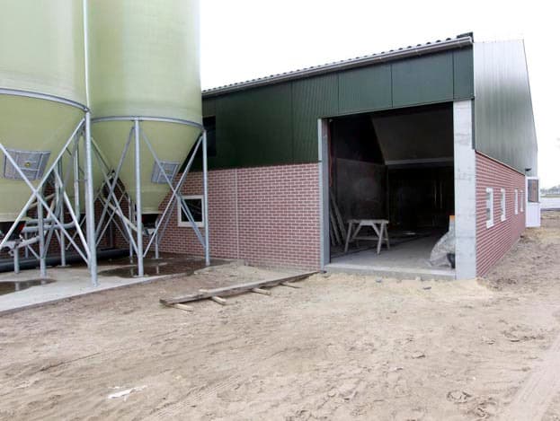 De luchtwasser, met rechts de spuiwatertank, bevindt zich aan de voorzijde van de stal.  Ik wilde de luchtwasser per se op de grond hebben. Ik heb op de thuislocatie ook twee luchtwassers. Deze staan wel boven. Ik vind dat niet praktisch."