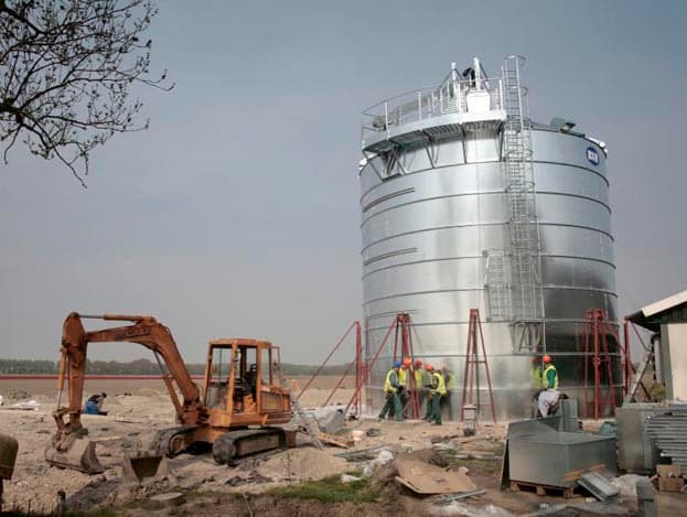 Bouwlieden werken aan de kooiladder. Doordat de ladder hoger is dan 10 meter moet er na 6 meter verplicht een rustbordes worden geplaatst.