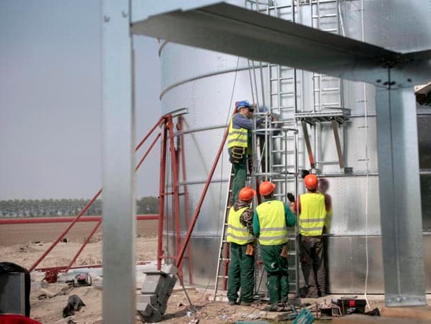 Bouwlieden zorgen dat de ringen van de silo goed aan elkaar vast komen te zitten.