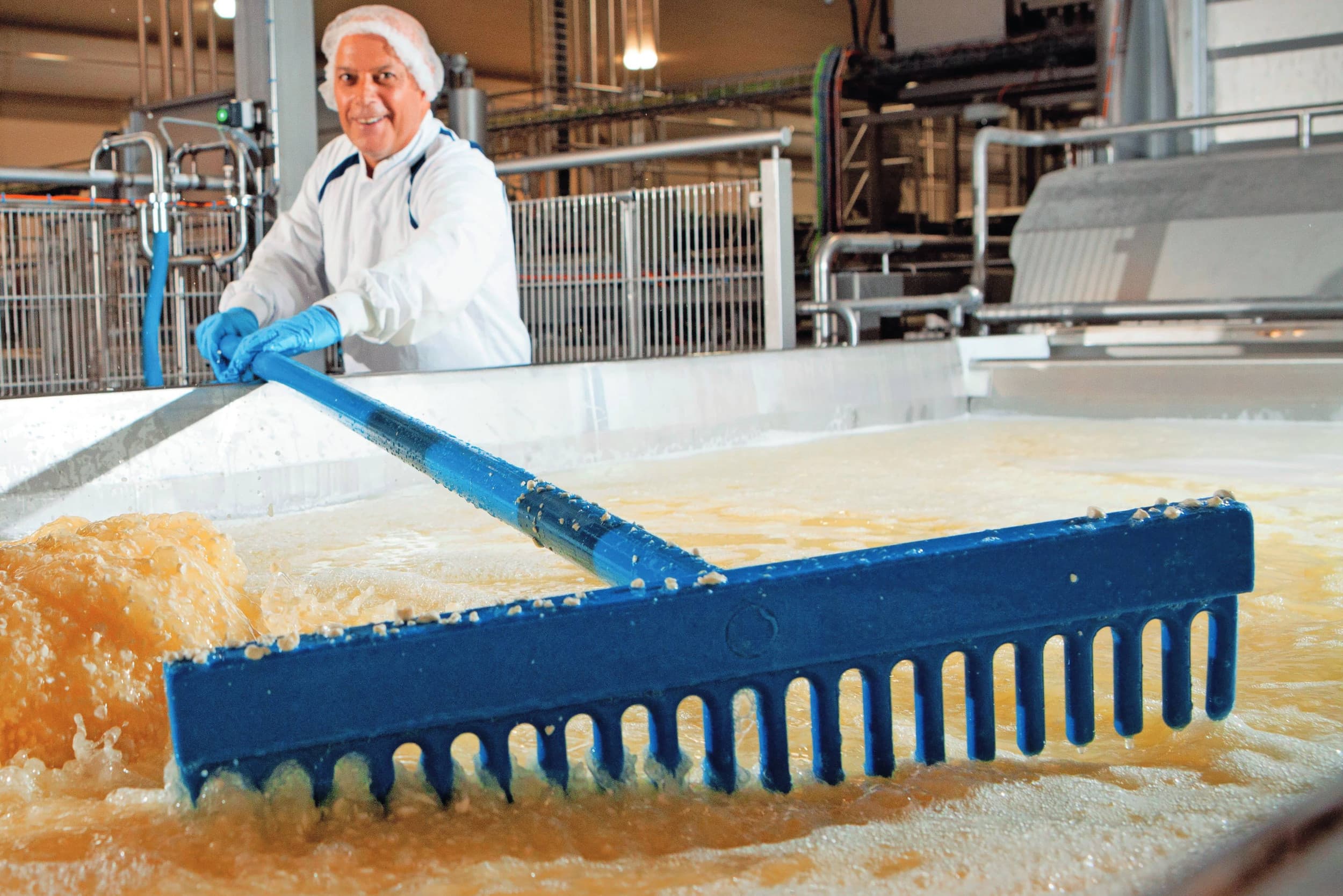 Kaasproductie: handmatig draineren. Minder papierwerk geeft ruimte voor initiatieven die wel verschil maken, zoals elektrificatie van productieprocessen bij Cono Kaasmakers. Foto: Misset