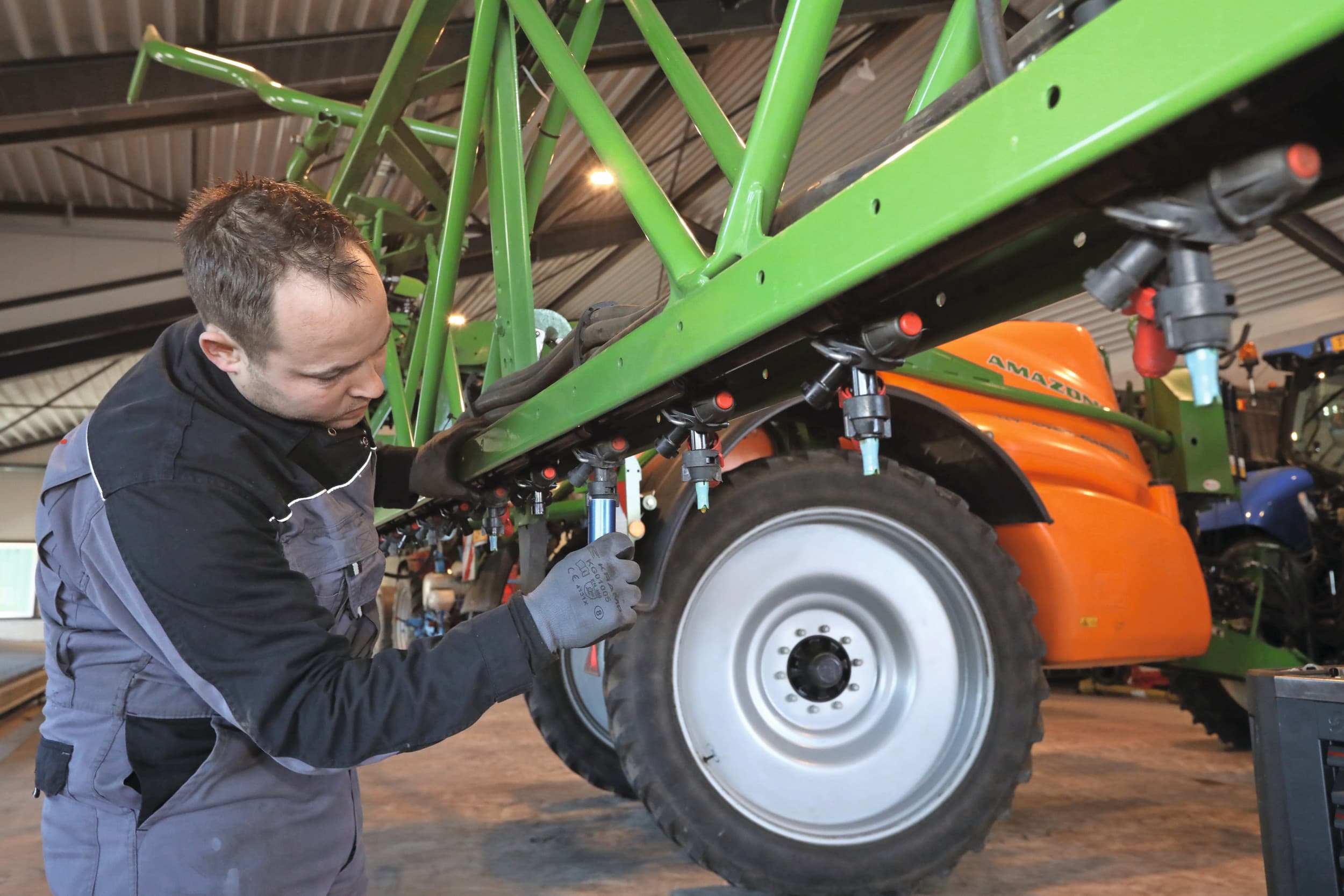 Een medewerker van mechanisatiebedrijf De Kruyf in Aalten (Gld.) bouwt een spuit om naar dopafstand van 25 centimeter. Foto: Henk Riswick