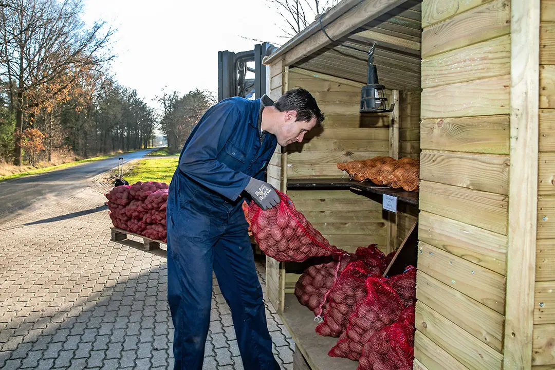 Hendri Broeze vult de kraam aan de weg weer aan met consumptieaardappelen. - Foto's: Ronald Hissink