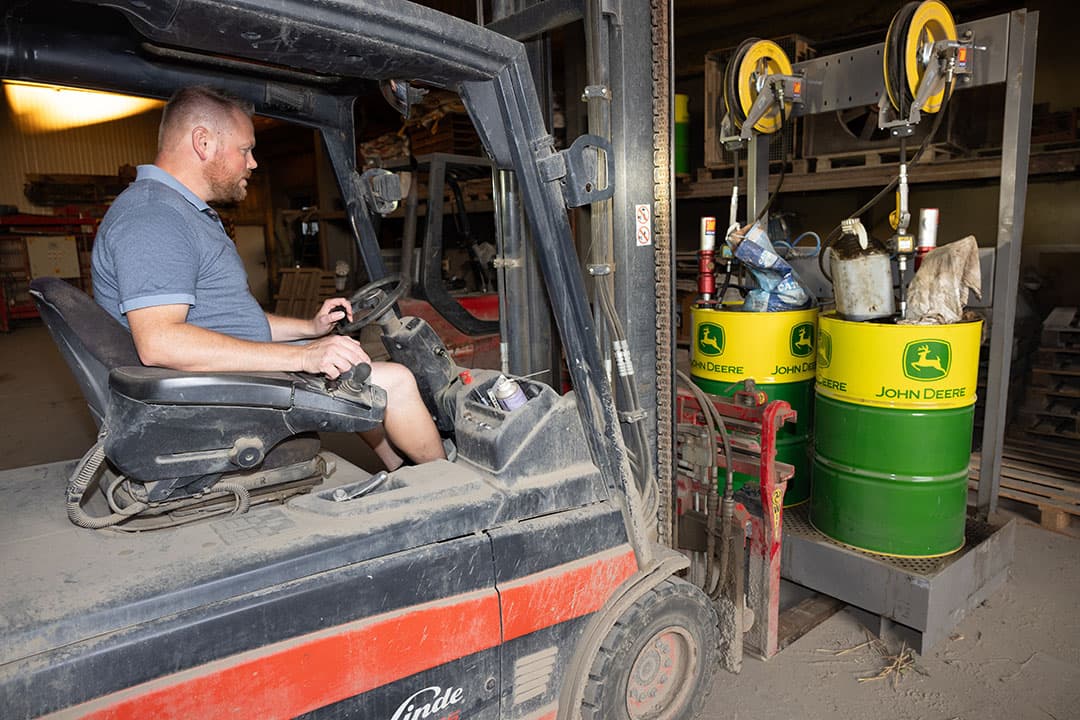 Marcel op de heftruck in de schuur.