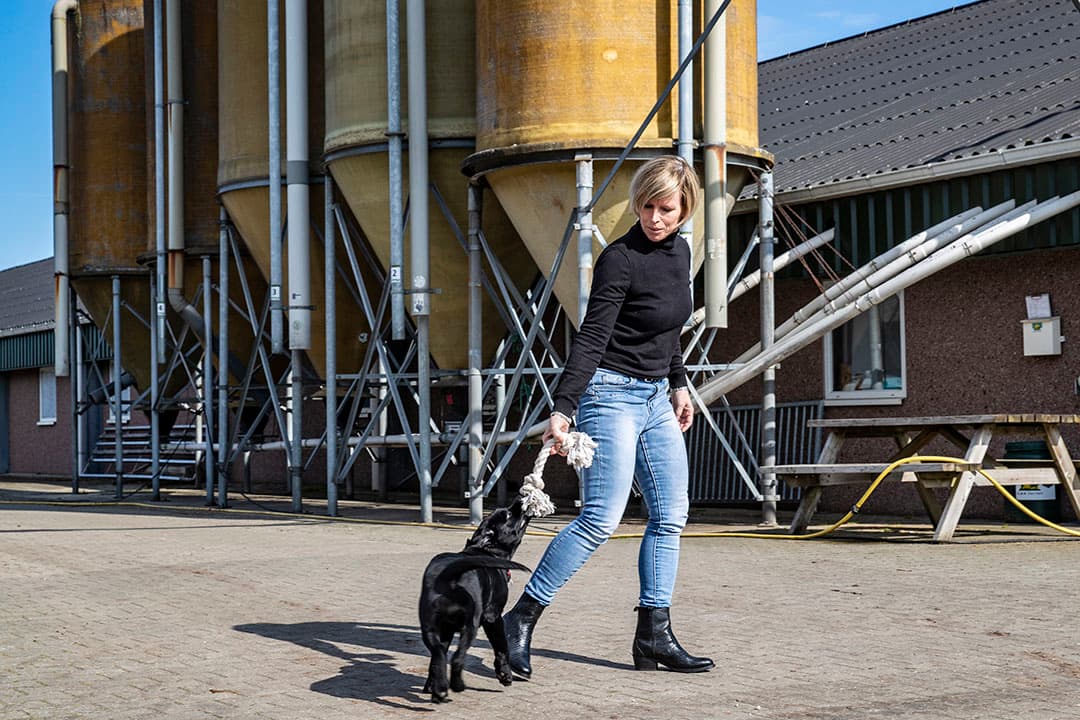 Gélinda met de pup op het erf. De varkens vond ze vroeger zielig maar nu niet meer. 'Ik ga met plezier de stal in.' - Foto's: Ronald Hissink
