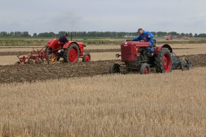 Twee Zeeuwse ploegnestors bezig op hun veld. Rechts Bas Martens uit Lewedorp met Steyr en Ransomes rondgaande ploeg. Hij werd in deze categorie Zeeuws kampioen met 149 punten. Links Adrie van Strien die ondanks de fysieke beperkingen opgedaan tijdens zijn 83 jaar geen ploegwedstrijd probeert over te slaan. De in het verleden regelmatig Zeeuws en Nederlands kampioen moest nu anderen voor laten gaan. Met 139 punten werd hij met zijn Hanomag en Cockshut rondgaande ploeg 4e.