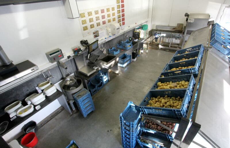 De aardappelen komen nu bij de optische sorteerder. Daar dienen ze op een vaste plaats doorheen te gaan. Lepels remmen de aardappelstromen zo nodig af voor een goede verdeling. Hier zijn al drie afwijkingen te zien doe de sorteerder er zonder meer uit zal halen. Een kluit, groenverkleuring en afwijkende vorm en maat.