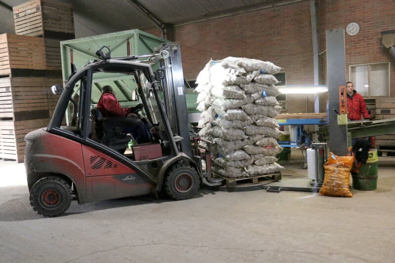 Marcel de Nijs plaatst een volle pallet op de wikkelschijf geplaatst om er folie om te wikkelen.