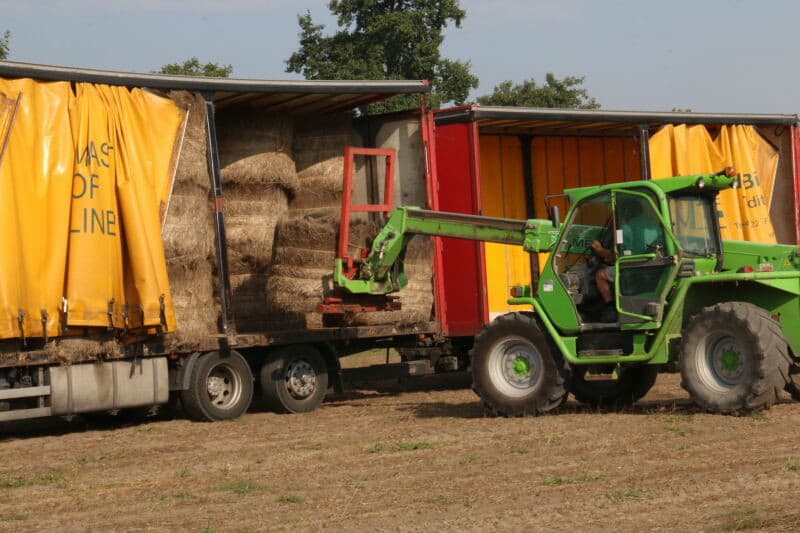 Inmiddels is een vrachtcombinatie gearriveerd, waarin de balen drie hoog worden geladen en naar een centraal opslagdepot worden gebracht.