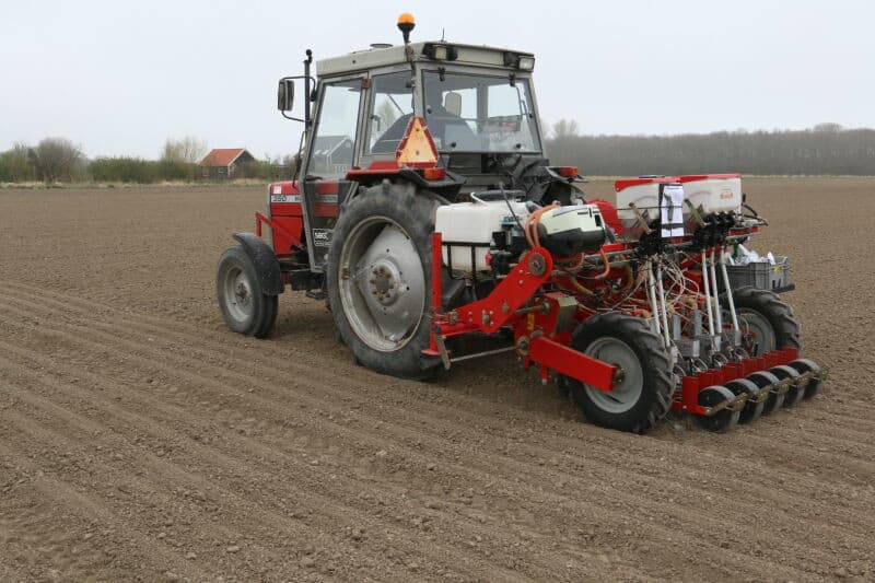De uitjes worden aangezogen boven de borstel en meegevoerd tot voorbij het hoogste punt. Daarna worden ze losgelaten in de kokerschijf, rood, die ze vervolgens op zijn laagste punt in de plantgeleider laat vallen om geplant te worden.
