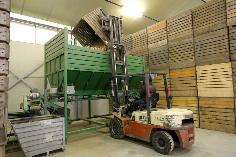 Vanuit de voorraadbunker gaat het pootgoed naar de kistenvuller. Tijdens dit transport gaat het pootgoed onder een pieperdoes, rechtsonder, waar het wordt behandeld met het middel Diabolo om bewaarziekten te voorkomen.