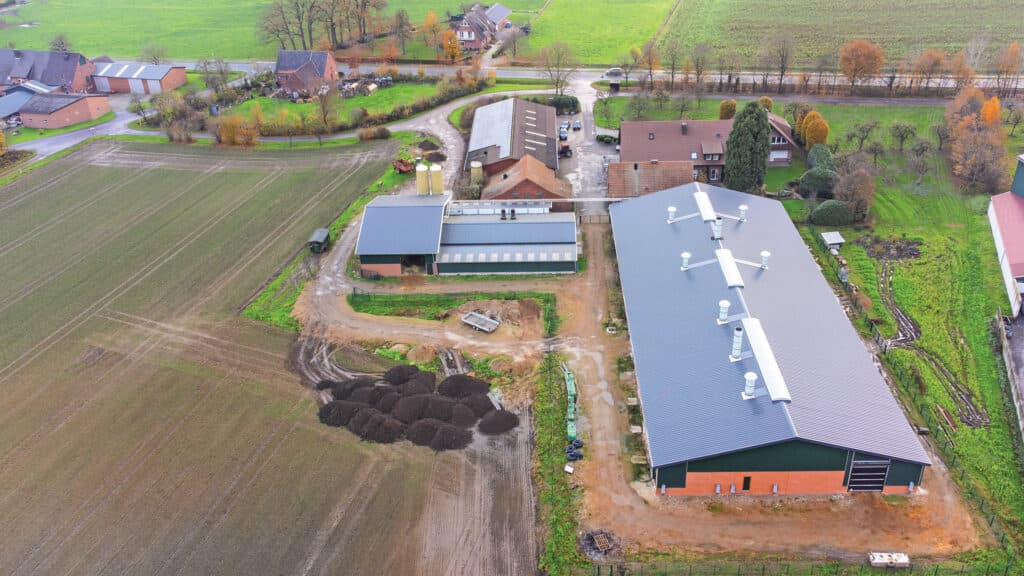 Op de voorgrond de nieuwe zeugenstal met uitloop. Links de biggenstal met voerkeuken en stro-opslag. Via leidingen wordt het voer en stro naar de nieuwe stal getransporteerd.