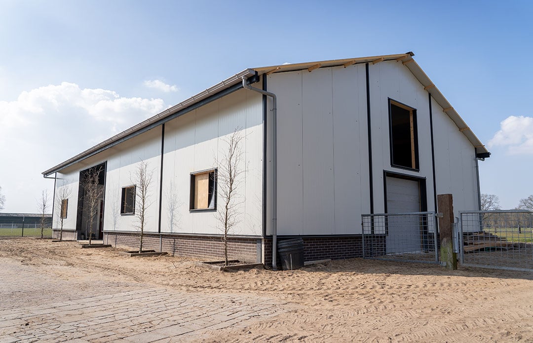 De nieuwe schuur van 20 bij 12 meter is bijna klaar. De gevelbeplating – zwarte potdekselplanken – ontbreekt nog. Druijff gebruikt de schuur als onderkomen voor zijn schapen en voor de opslag van machines.