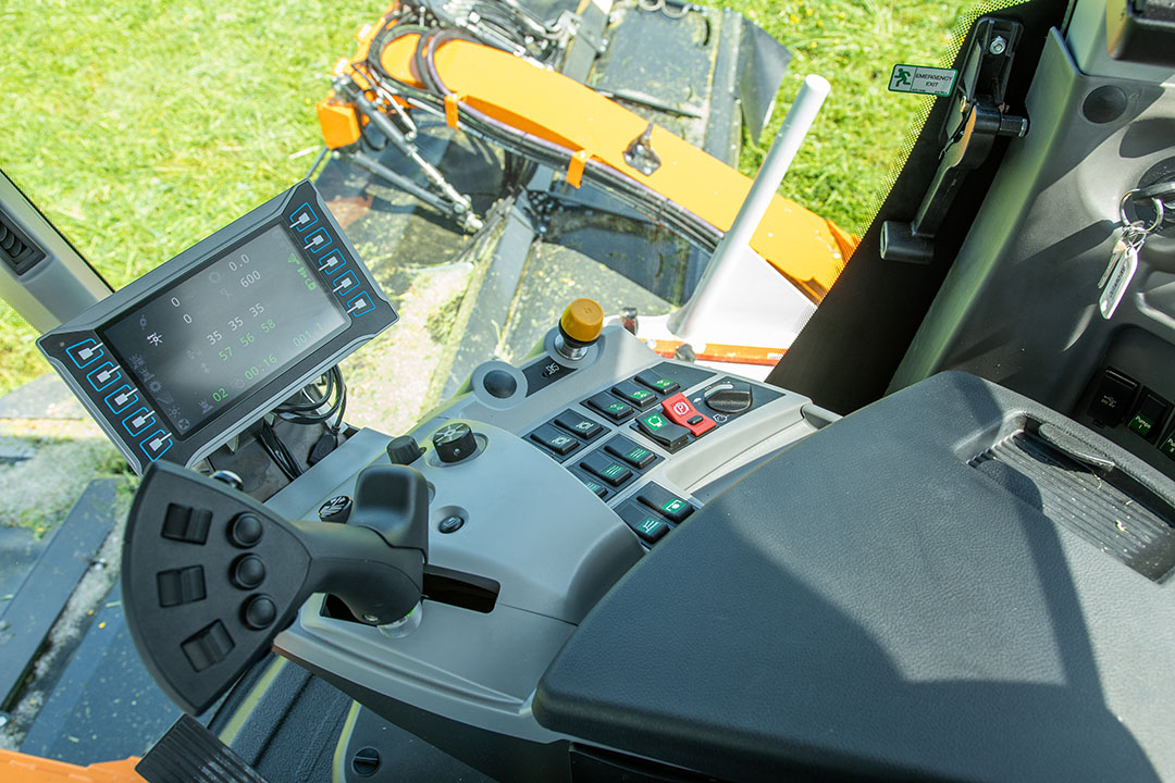 De machinebouwers ontwierpen een eigen rijhendel en monitor. Alle belangrijke zaken zijn erop te volgen. Let ook op het zicht op de zijmaaier. Die is tijdens het werk mooi in beeld.