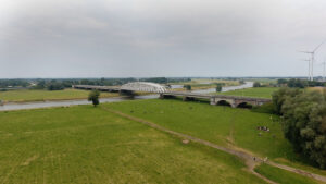 De koeien lopen in de uiterwaarden. Aan de andere kant van het bedrijf liggen de stad en industrie.