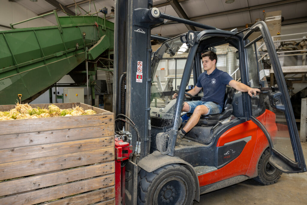 Bram met een kuubskist knolselderij. Hij rijdt af en aan. In een halve dag gaat er zomaar 200 ton door de wasserij. Bram heeft een kroegje aan huis waar hij graag met vrienden zit, maar op het moment is daar geen tijd voor.