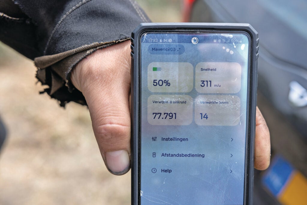 Op het scherm van zijn smartphone ziet Emiel van Hootegem de status van de Odd.Bot, die draait op een veld met uien op ruggen. Foto: Peter Roek